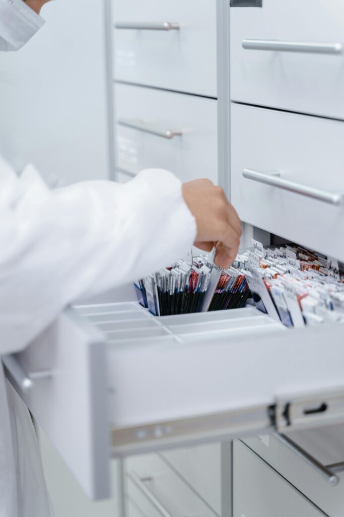 A person wearing a lab coat organizing files in a medical laboratory drawer.